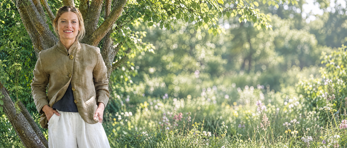 Woman wearing an Artemesia linen blazer in a sunlit garden
